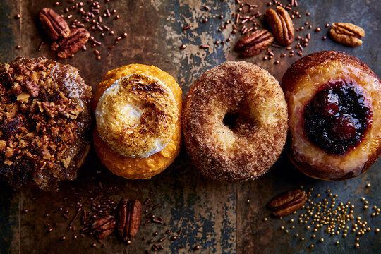Overhead view of a row of Thanksgiving pie-themed donuts on a distressed dark table