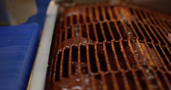 Lean slices of raw meat with a thin rim of fat lying on a metal grate in a food facility