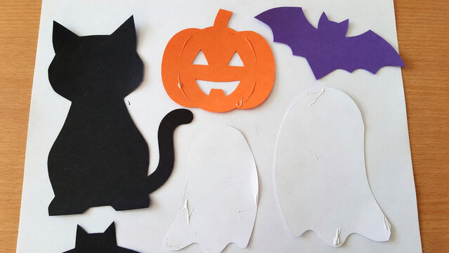 Cutout shapes of black cat, pumpkin, bat, and ghosts for Halloween  