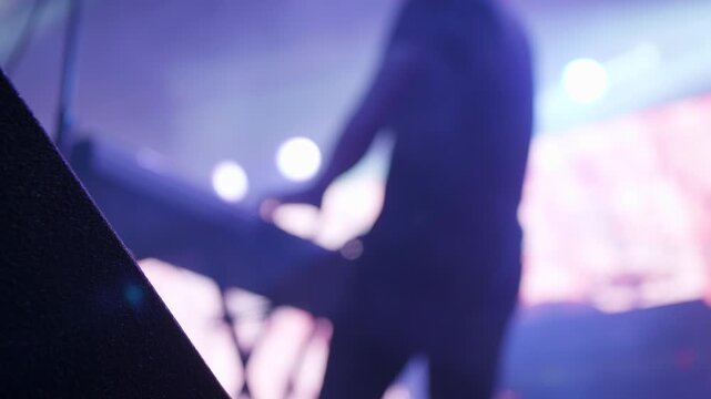 Man plays electric piano under strobe lights on stage, creating a bright rock concert moment with synthesizer rhythm and festival energy.