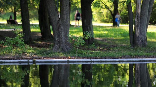 Unrecognizable people walking on the streets of Warsaw. People walking in the park. Sunny, hot, summer weather.