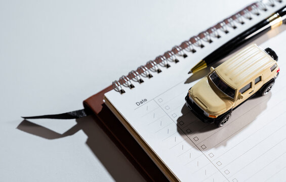 Car purchase concept. Model vehicle on planner symbolizes auto financing and transportation preparation, budget, loan, insurance, mobility, ownership