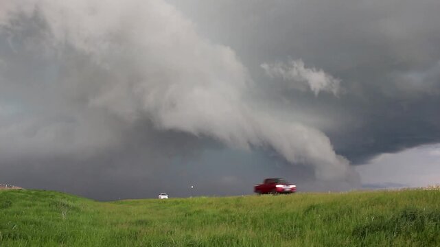 A severe storm with a shelf cloud approaches on the prairie as cars drive down the highway. Time lapse footage.