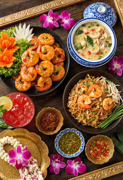 Authentic Thai cuisine flat lay featuring Pad Thai, spicy glazed shrimp, and coconut curry served on a wooden table with orchids