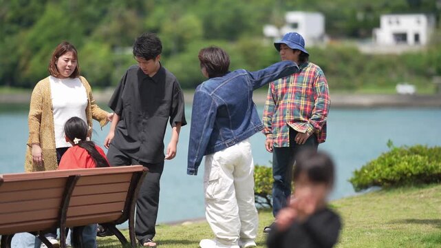 Family gathers near lakeside bench. Children laugh as adults chat nearby. Soft light bathes green hills and calm water. Perfect for family, leisure, or outdoor scene needs