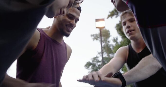 Diverse male pals huddling leader giving pep stacking breaking and playing basketball on blue court