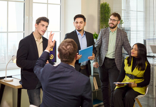 Businesspeople team in office meeting discussion. Colleagues gather around a manager for presentation and planning a project in a bright workspace. Teamwork leadership and collaboration concept.