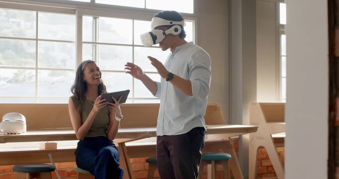 Diverse coworkers testing VR demo after man putting on headset, woman operating tablet, laughing