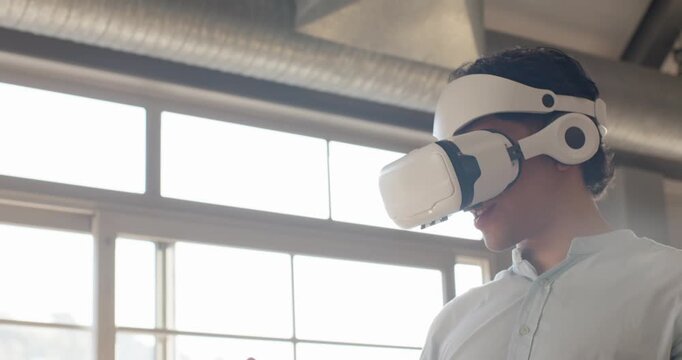 Team watching Asian man starting VR headset demo, raising right hand, testing with tablet and watch