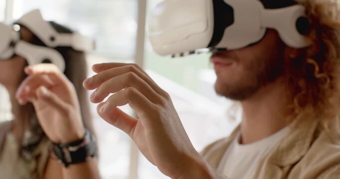 Diverse friends, man on right gesturing and exploring interface after white headsets prompt in loft
