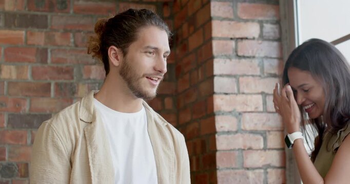 Diverse coworkers reacting as standing man sharing smartphone meme woman laughing at brick wall