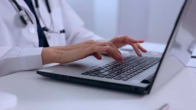 Doctor laptop keyboard hand typing medical stethoscope clinic healthcare physician online patient record telemedicine consultation modern technology professional work focus