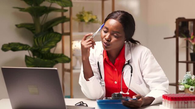 Female doctor in lab coat sitting at desk, analyzing medical information on laptop