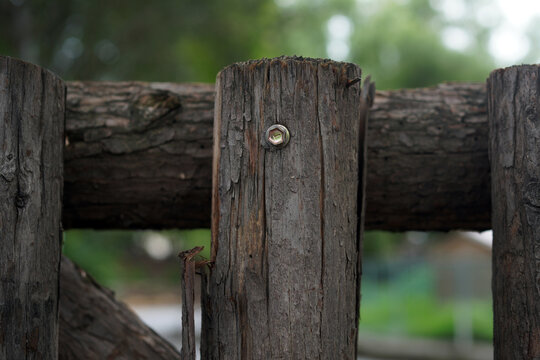 Close-up of a weathered wooden fence post with a metal screw