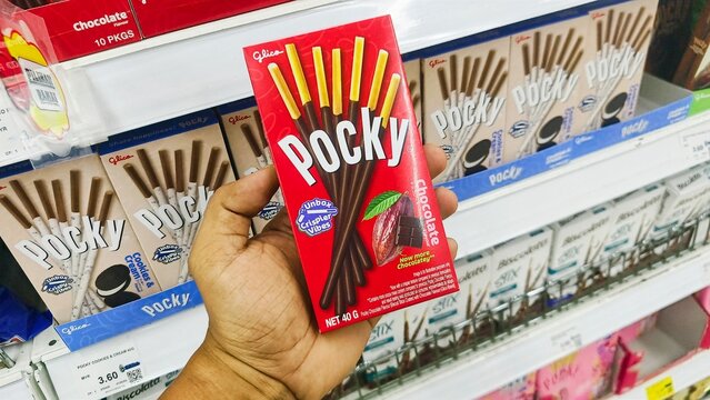 Malaysia Kuala Terengganu 18 July 2026: Hands holding products Assorted packs of POCKY biscuit stick display for sell in the supermarket shelf with selective focus.