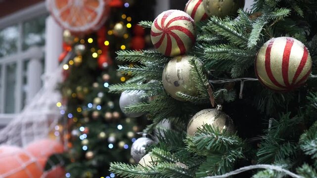 New Year's video card with fir branches decorated with garlands and Christmas balls in gold color in red stripes against the background of shimmering multi-colored garlands and giant tangerines in a