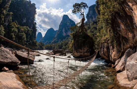 Rustic rope bridge across mountain river in Thailand landscape