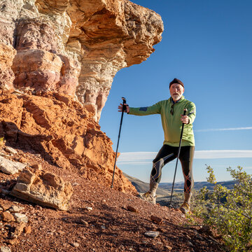 senior hiker in his 70s with trekking poles enjoying scenic views in Red Mountain Open Space in northern Colorado