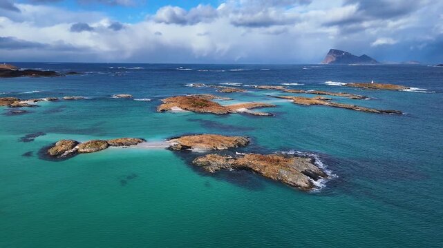 Aerial view of rocky islets and reefs in turquoise ocean water in Sommaroy, Norway