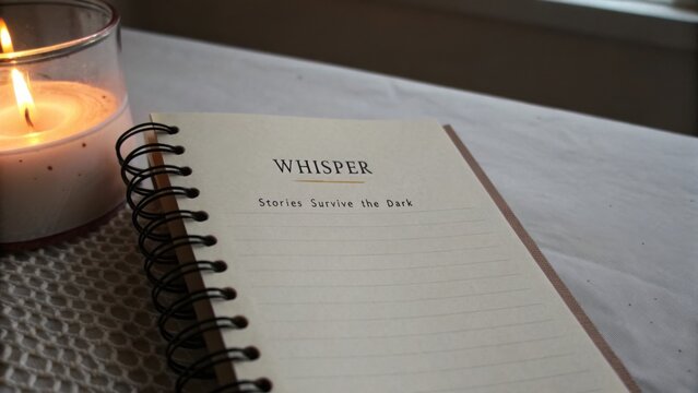 Cozy candlelit setting with an open notebook and the word Whisper, inviting creativity and reflection in a tranquil atmosphere