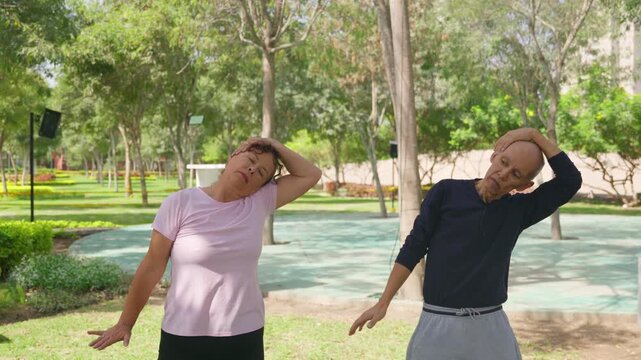 Senior couple and instructor performing neck stretching exercises in a park