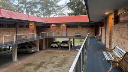 Fototapeta premium Two Story Brick Motel Courtyard with Red Tiled Roof During Rain