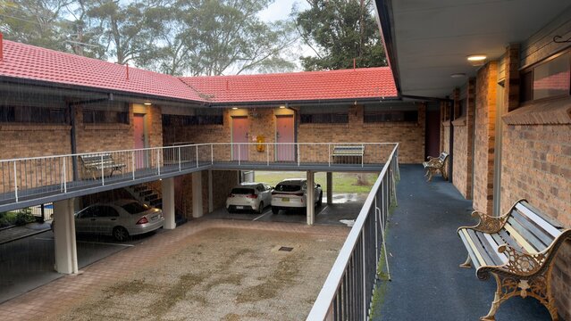 Two Story Brick Motel Courtyard with Red Tiled Roof During Rain