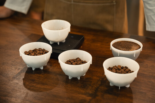 Specialty Coffee Cupping Samples with Roasted Beans and Ground Coffee Arranged in Tasting Bowls on a Professional Cafe Table