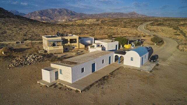 Small Mediterranean-style houses in a rural desert landscape, blue and white Agios Theodoros chapel, drone shot, evening light, Paralia Agios Theodoros, Agios Theodoros Beach, south-west coast, Karpathos, Dodecanese, Greek Islands, Greece