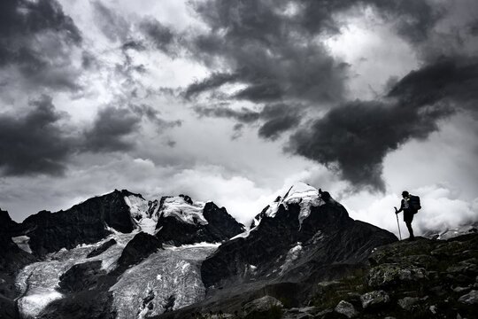 Climbers in front of summit of Bernina Group with dramatic clouds, St Moritz, Engadin, Graub&uuml;nden, Switzerland