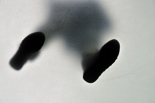Anonymous person standing with feet wide apart, from below