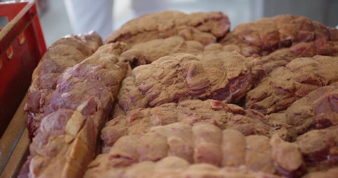 Seasoning powder falling onto large pieces of raw meat lying close together in a butchery