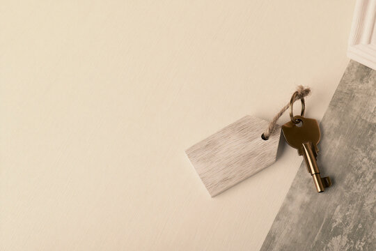 Single brass house key with a wooden tag real estate and home concept