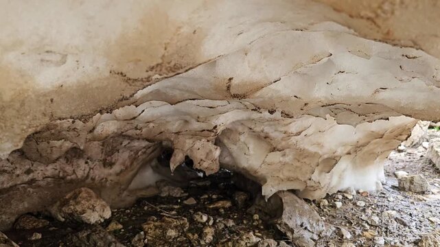Meltwater drips from a snow cave overhang onto a rocky ground below, with layered ice and snow textures forming the cave ceiling.
📍 Hawraman Takht, Kurdistan, Iran 