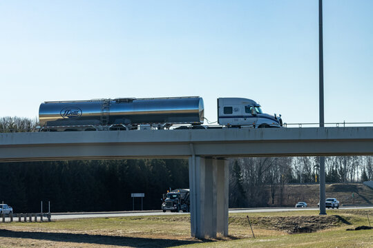 Quebec, Canada, 24 April 2026 : A white semi-truck with a silver tanker trailer, branded "Petit", drives on an overpass above a highway.