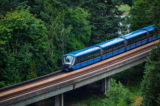 Skytrain travels through green trees in Vancouver, Canada during a clear day