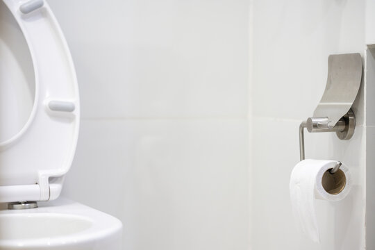 White toilet bowl and tissue paper roll in the bathroom at home.Ceramic wc bowl and roll of toilet in bathroom with modern interior.Modern toilet concept.