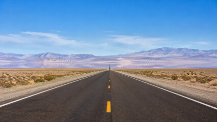 Obraz premium Endless asphalt highway vanishing into arid mountainous horizon under clear blue sky with evoking sense solitude adventure dry expansive desert landscape