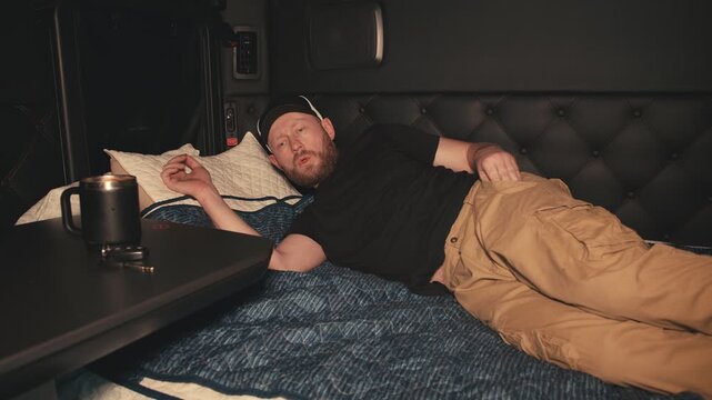 Truck driver waking up to alarm on phone in sleeper cab