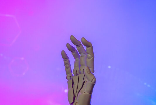 Mechanical hand reaching upward against a vibrant neon pink and blue gradient background. Artificial intelligence, virtual reality, futuristic technology, cybernetics concept.