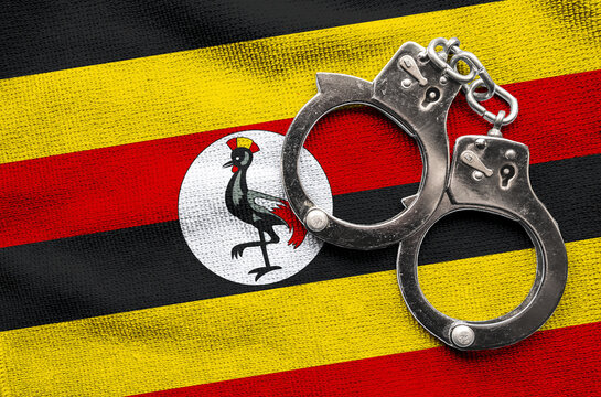Flag of Flag of Uganda and police handcuffs. Crime and offenses in country Concept
