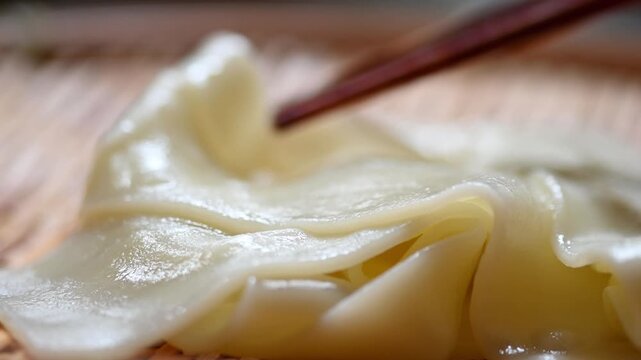 ざるに乗ったツヤのある幅広うどんと箸のクローズアップ