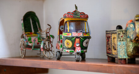 Naklejka premium Colorful miniature tuk-tuk and traditional rickshaw souvenirs on a wooden shelf