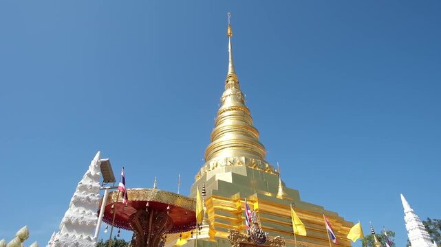 Golden Lanna style pagoda  of Wat Phra That Chae Haeng temple with flags waving in the wind, Nan Thailand