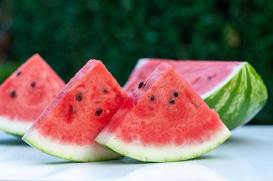 Fresh Watermelon Slices on White Table with Natural Green Bokeh
