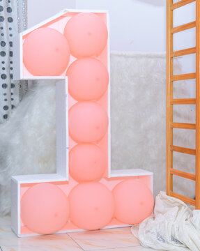 Number one balloon display with pastel pink balloons for a first birthday celebration decoration
