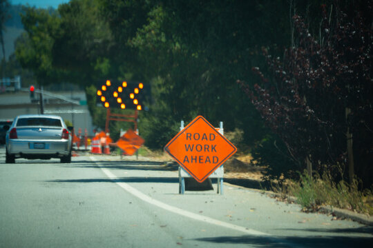 Road work ahead sign with flashing arrow directing traffic to the left