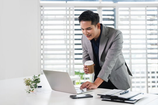 Businessman using laptop computer in office. Happy middle aged man, entrepreneur, small business owner working online.