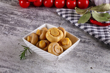Fototapeta premium Marinated champignon mushrooms in white bowl with herbs and cherry tomatoes