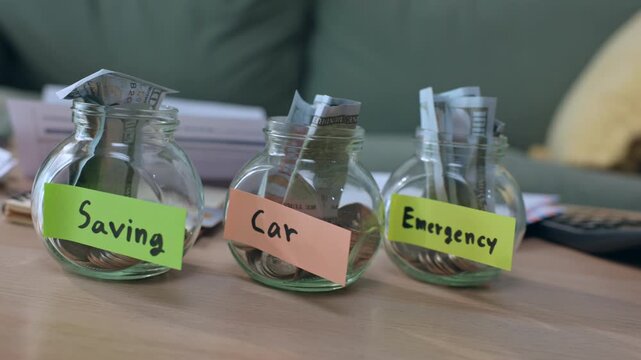Saving car emergency jar money cash coin glass budget finance plan with labeled containers on wooden table for personal goal expense reserve fund household cash management concept